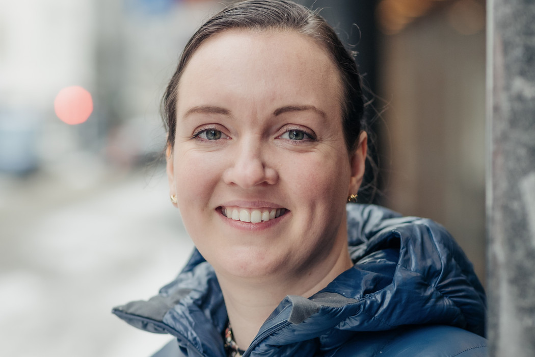Nærbilde av kvinne som smiler. Hun er utendørs og har boblejakke på.