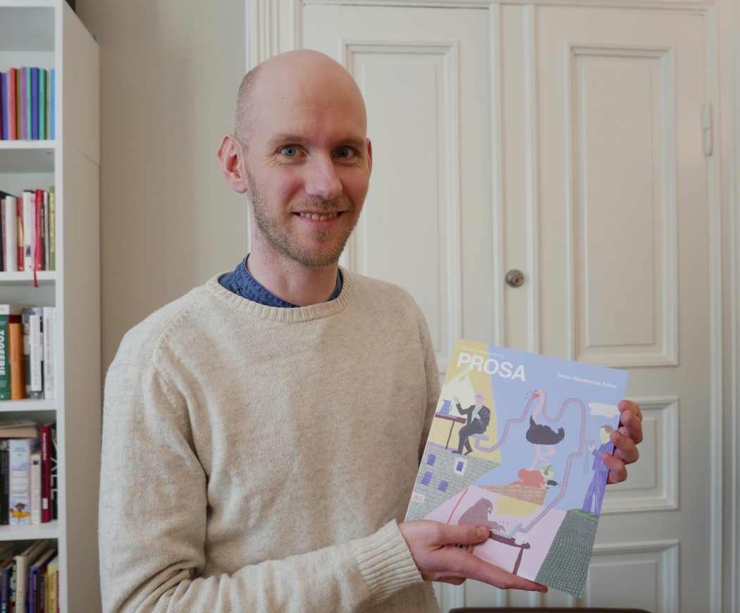 Mann som holder et tidsskrift i hendene