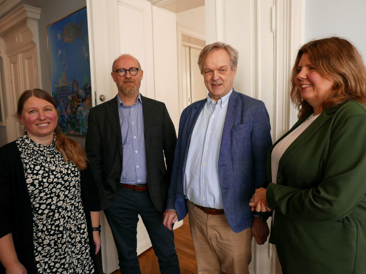 To kvinner og to menn som står foran en åpen dobbeldør.